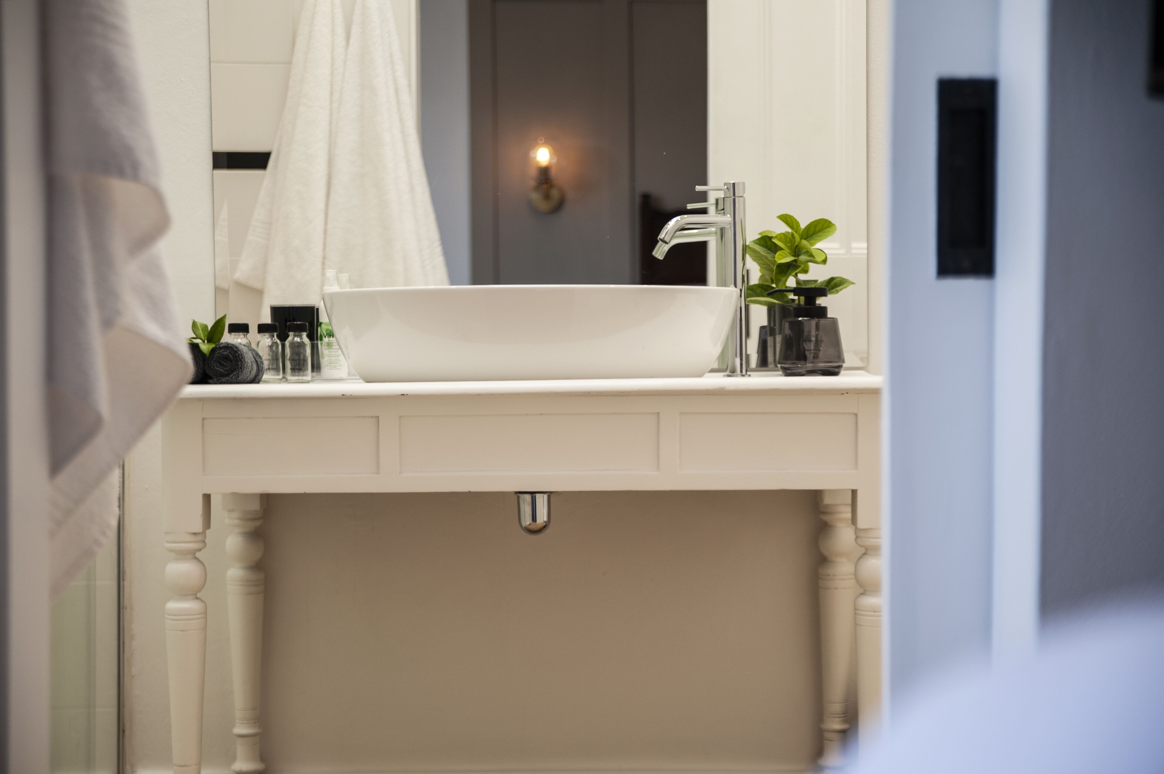 A bathroom with a white sink, a mirror, a towel, and a potted plant.