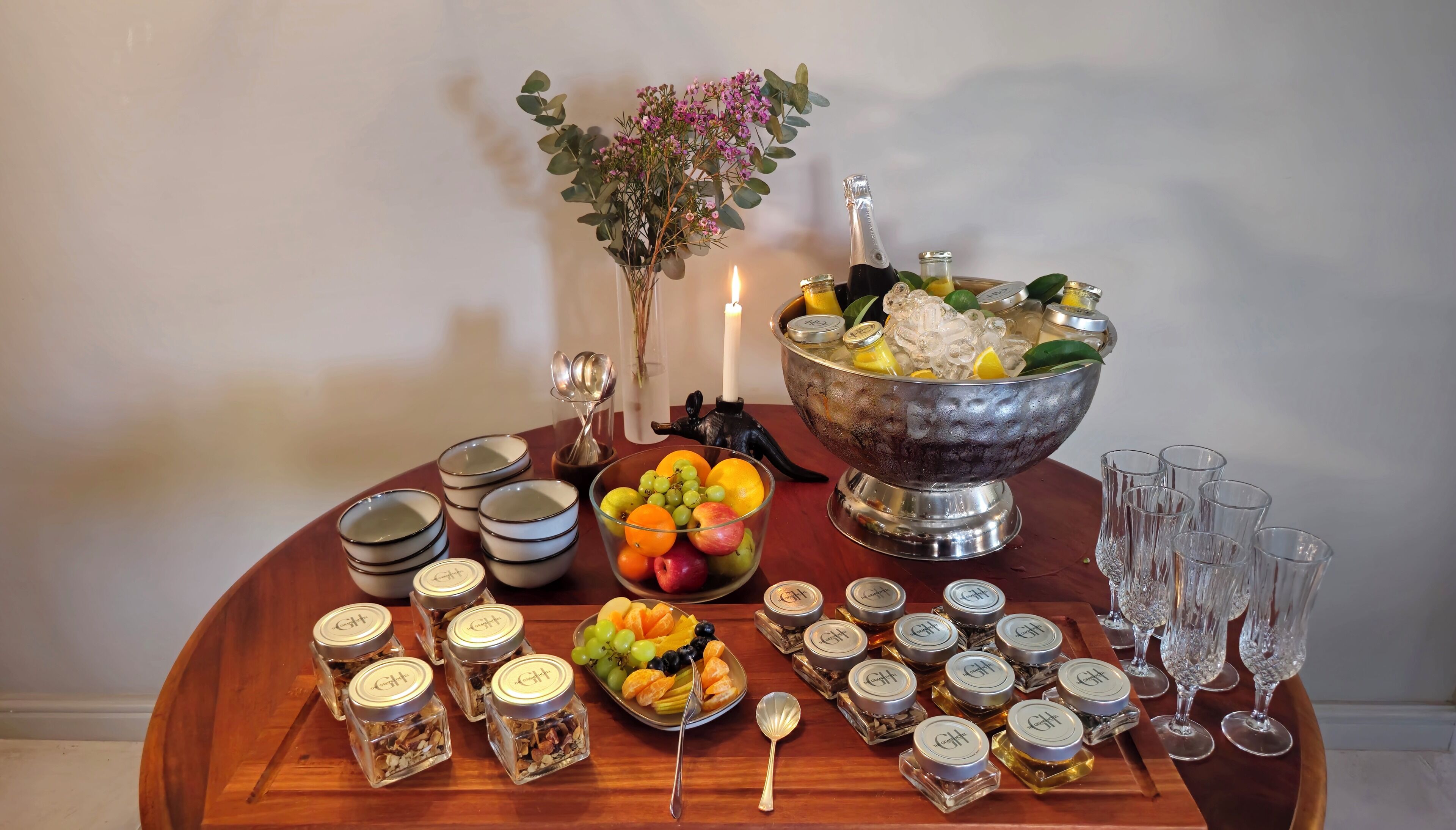 Ein Tisch mit Obstschale, Kerzen und Gläsern mit Marmelade.