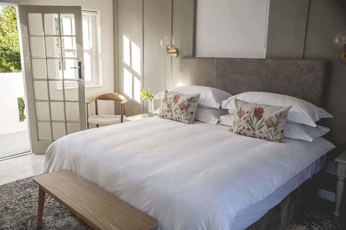 A bedroom with a large bed, a bench, a chair, and a nightstand.