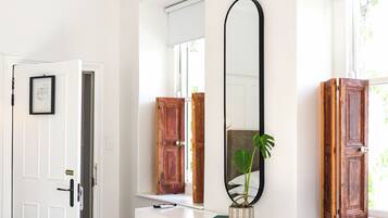 Una habitación blanca con escritorio, silla y espejos grandes.