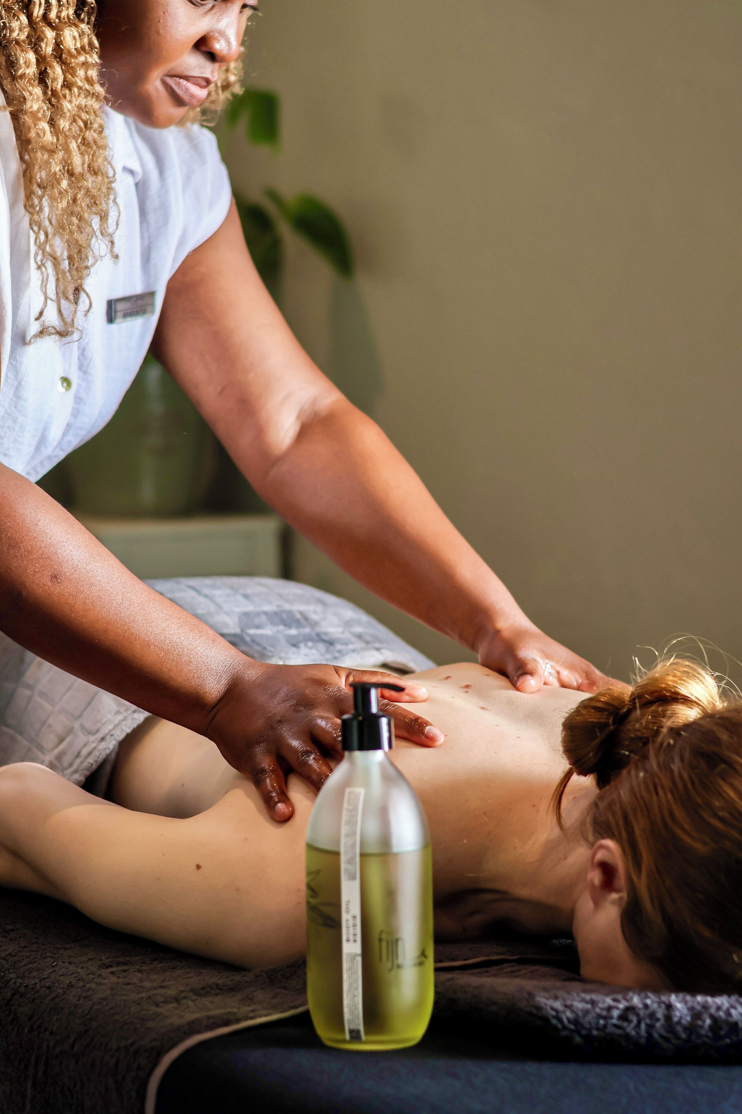 Eine Massageanwendung mit einer Flasche Öl auf dem Tisch.