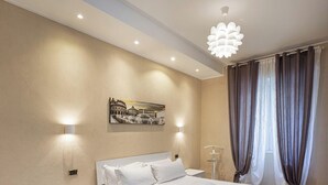 Een moderne slaapkamer met een groot bed, een schilderij van een historisch gebouw en een bord met daarop ‘smart working’.