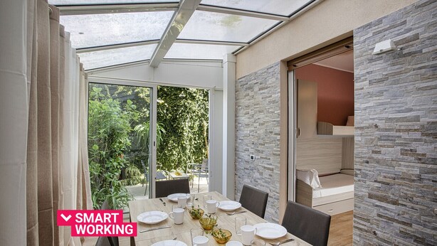 A modern dining area with a glass ceiling, stone wall, and a view of greenery outside. - Modern Apartment in Rapallo by Wonderful Italy (Rapallo)