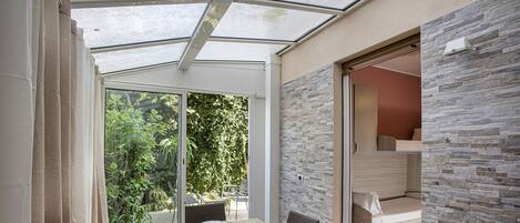 Ein moderner Essbereich mit Glasdecke, Steinwand und Blick auf die grüne Umgebung.