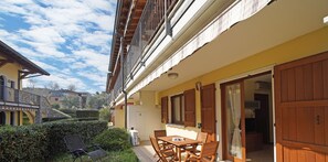 Un patio con tavolo e sedie, un piccolo giardino e un edificio con un balcone.