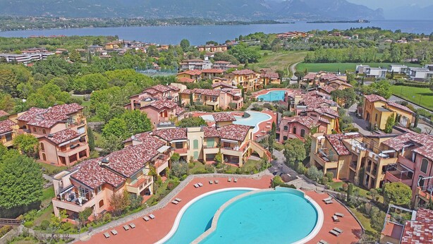 Un resort con diversi edifici, una grande piscina e vista su un lago.