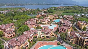Un resort con diversi edifici, una piscina centrale e vista su un lago.