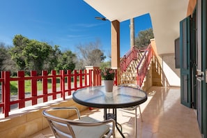 A covered outdoor patio with a round table and chairs, a red fence, and a staircase leading to an upper level. - 3839 La Dolce Casa by Barbarhouse (Melendugno)