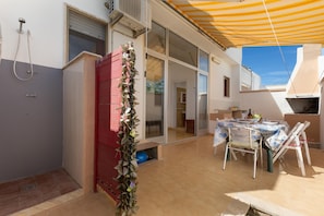 A covered patio area with a table and chairs, a red cabinet, and a shower. - 3839 La Dolce Casa by Barbarhouse (Melendugno)