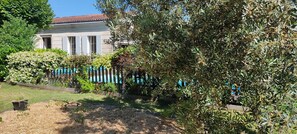 A house with a garden, a blue fence, and a tree in the foreground. - Maison Familiale Climatisee, Piscine Chauffée Sécurisée aux Portes de Bordeaux (Blanquefort)