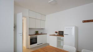 A compact kitchen with white cabinets, a wooden countertop, a built-in oven, and a white refrigerator. - Residence Orti 18 by Wonderful Italy (Salò)