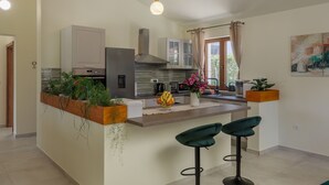 A modern kitchen with a central island, bar stools, and a view of the outdoors. - Villa Alora Zadarvillas (Novigrad)