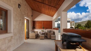 A covered patio with wicker furniture, a grill, and a view of a hillside. - Villa Alora Zadarvillas (Novigrad)