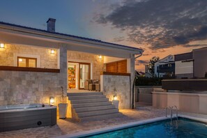 Uma casa moderna com fachada de pedra, piscina e área de varanda coberta.