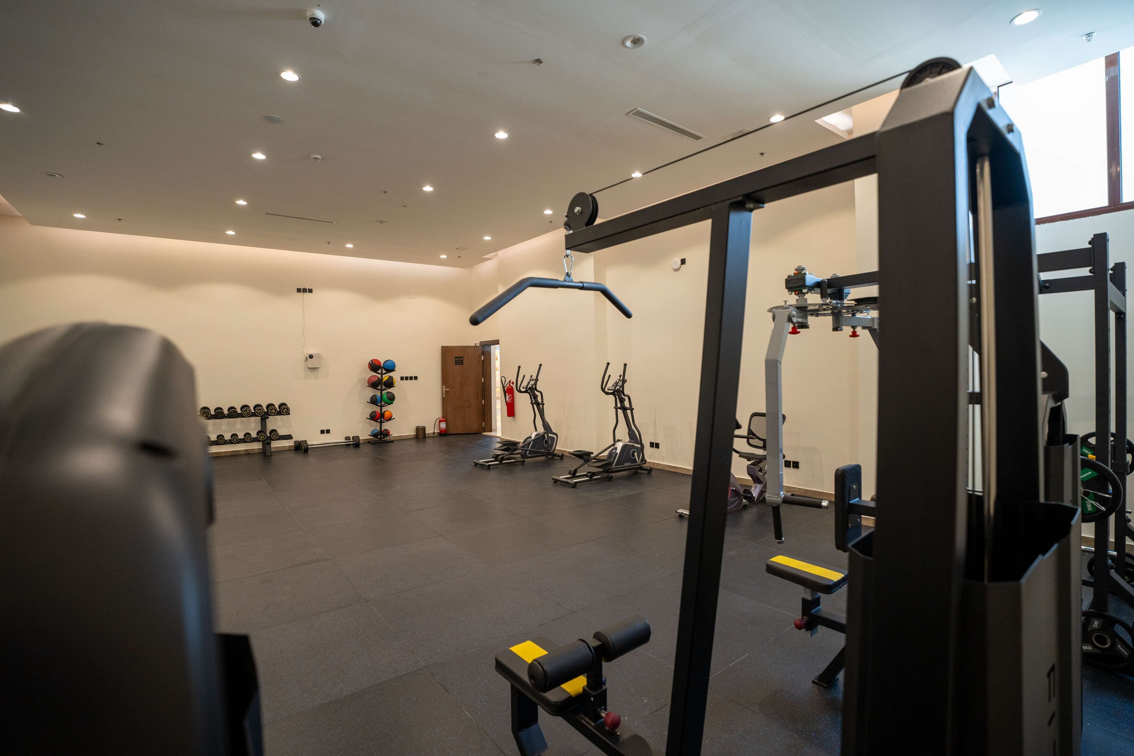 A gym with exercise equipment, weight racks, and treadmills.