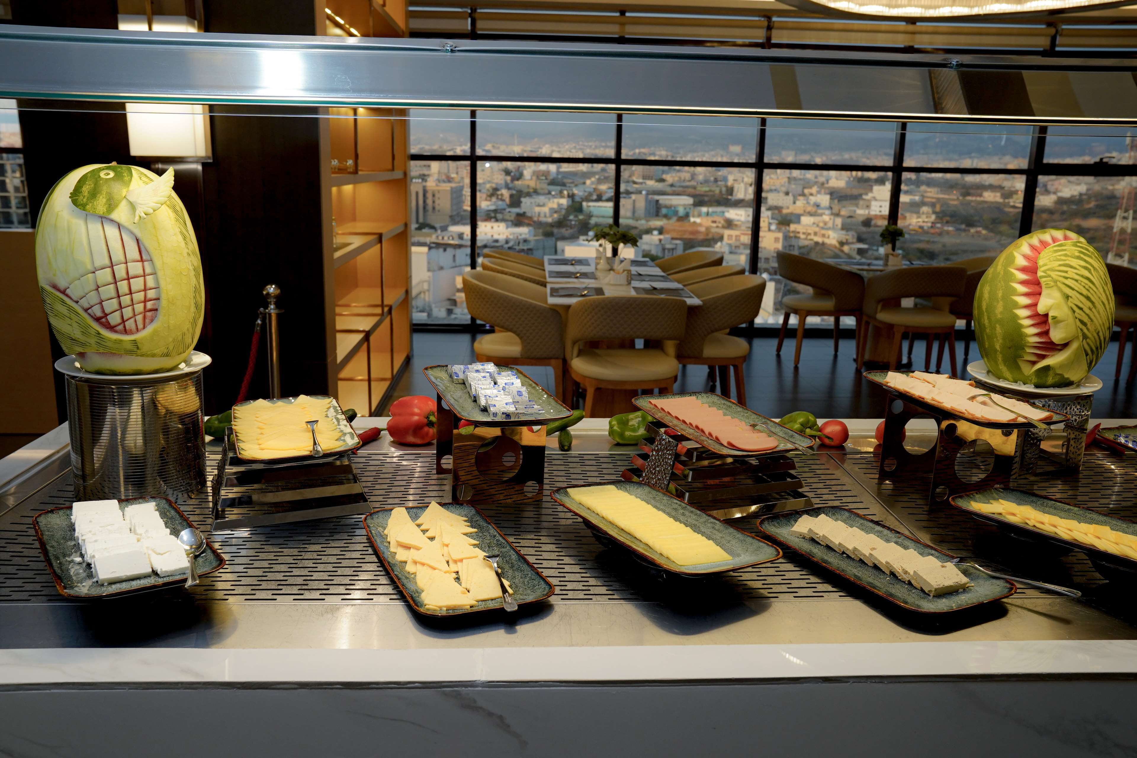 A buffet with various food items and decorative fruit carvings.