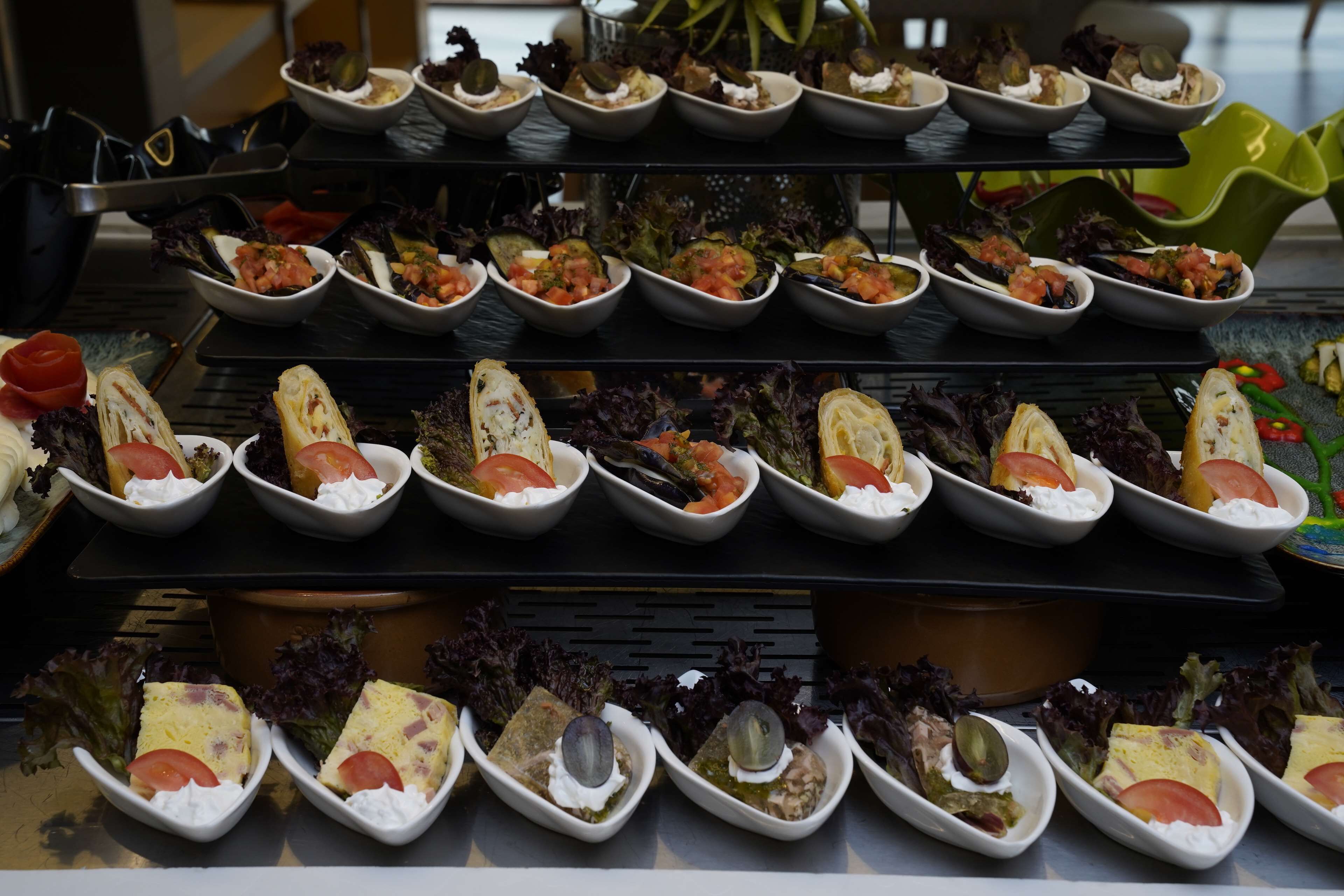 A buffet with various dishes arranged in bowls and plates, including salads, bread, and other appetizers.