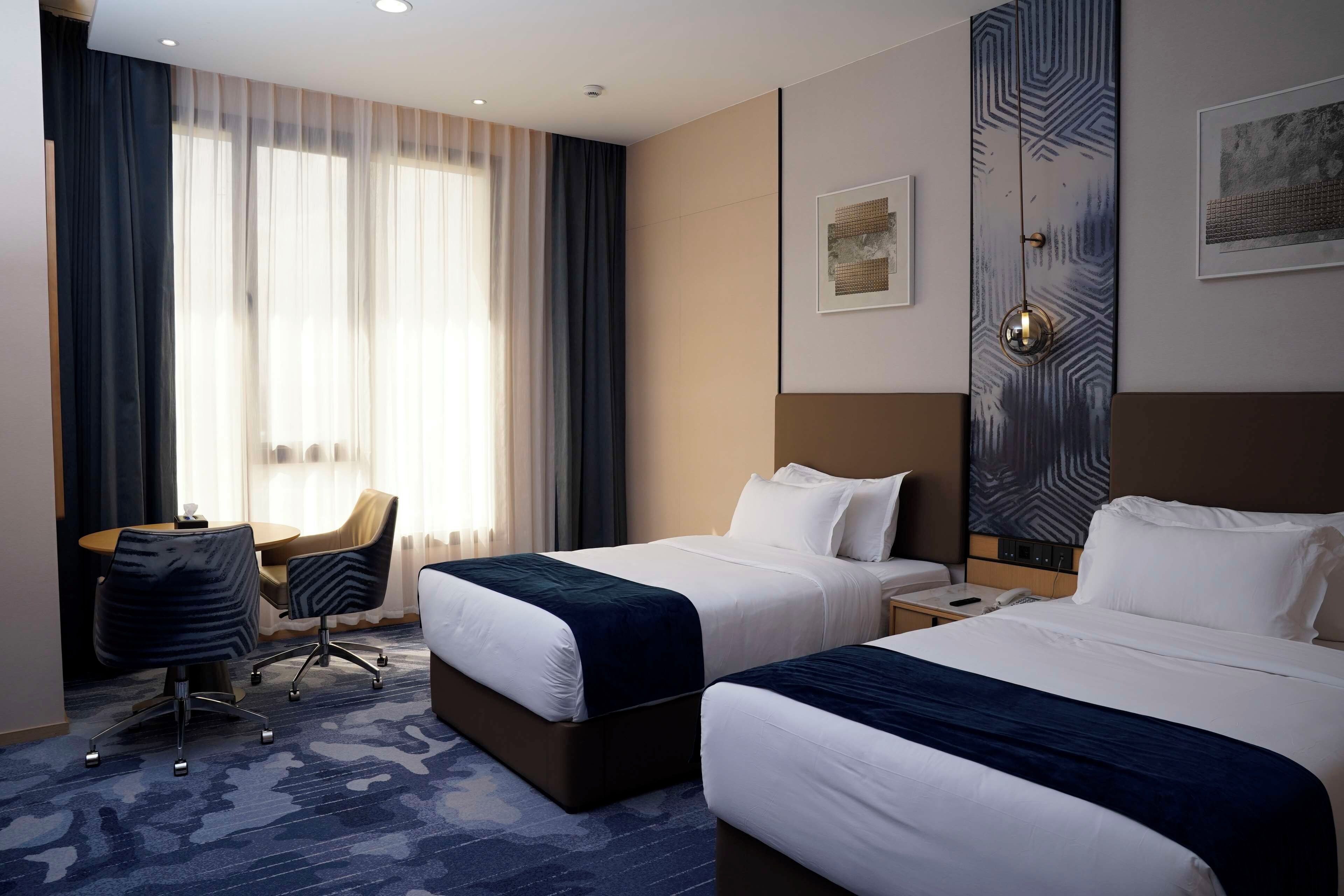 Ein Hotelzimmer mit zwei Betten, einem Schreibtisch und einem Sessel.