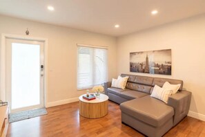 A modern living room with a grey sectional sofa, a round coffee table, and a cityscape painting on the wall. - Urban Escape Haven (Miami)