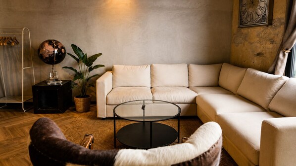 A living room with a sectional sofa, a round coffee table, a potted plant, a globe, and a ladder against the wall. - Nordic Hostel (Reykjavik)