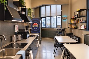 Une cuisine moderne dotée d’appareils électroménagers en acier inoxydable, d’une grande fenêtre et du logo Pepsi.