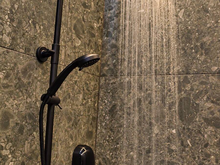 Une douche dotée d’un pommeau de douche imitant une pluie fine, d’un pommeau de douche à main et d’un panneau de commande.