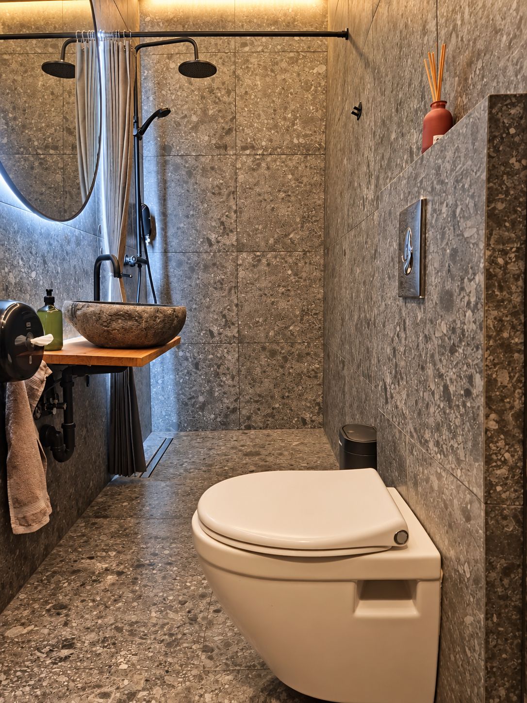 A modern bathroom with a freestanding toilet, a marble sink, and a shower area.