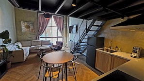 A modern kitchen with a dining area, a staircase, and a large window.