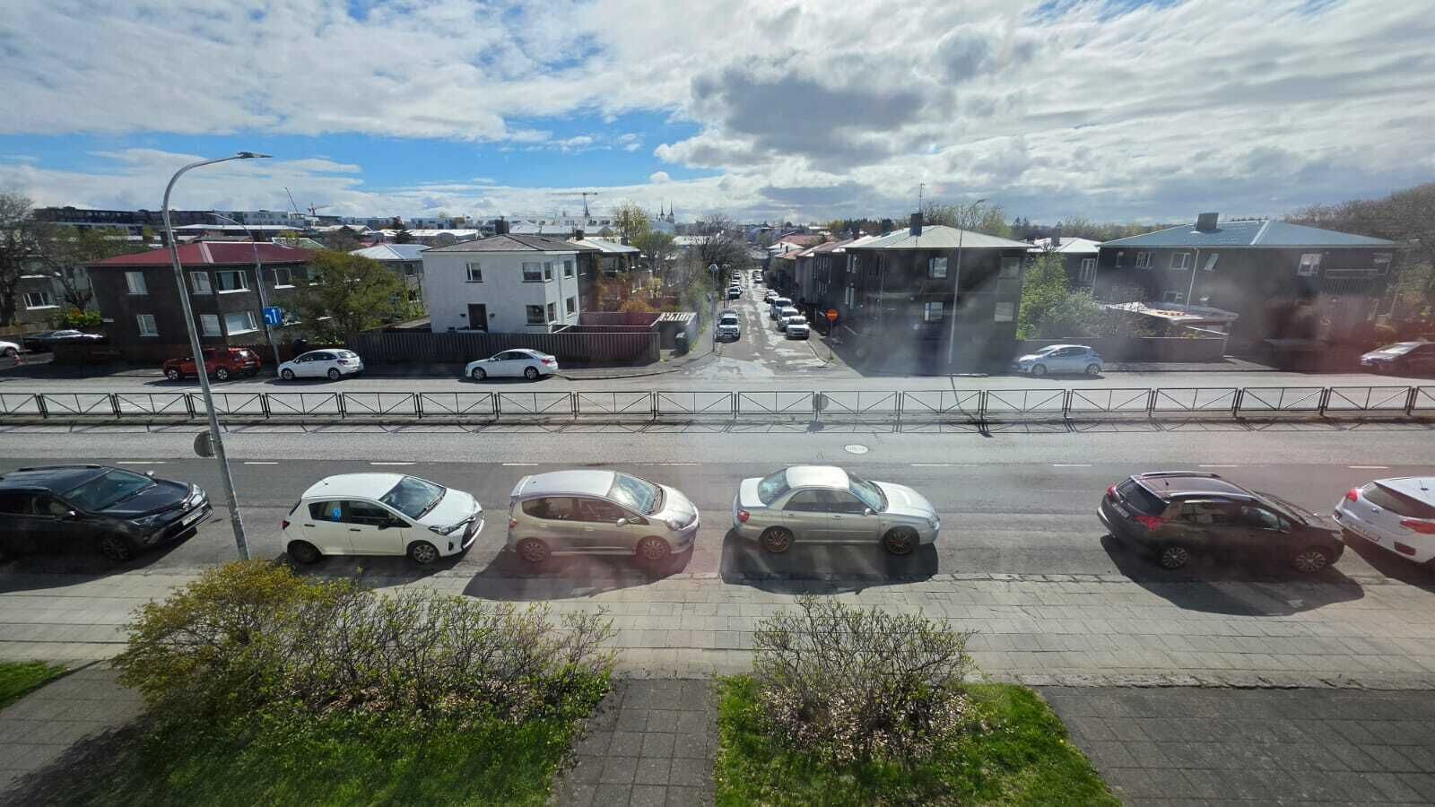 A multi-story building with a flat roof, a parking lot with several cars, and a clear sky.