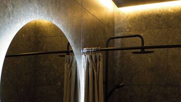 A modern bathroom with a round mirror, a sink, and a shower area.