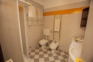 A bathroom with a checkered floor, a toilet, a bidet, and a bathtub. - Relax by the Pool Comfy Flat in Rosolina Mare (Rosolina)