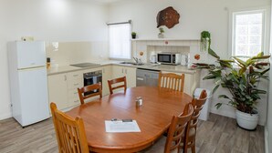Une cuisine compacte comprenant une table à manger, des chaises, un réfrigérateur, un four à micro-ondes et un évier.