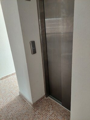 A corner of a room with a metallic elevator door and a textured wall. - Rent Apartment by the sea in Bulgaria, Sveti Vlas, Fort Noks Prestige (Nessebar)