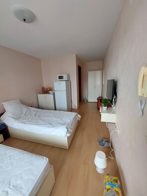A hotel room with a bed, a small desk, a microwave, a television, and a telephone. - Rent Apartment by the sea in Bulgaria, Sveti Vlas, Fort Noks Prestige (Nessebar)