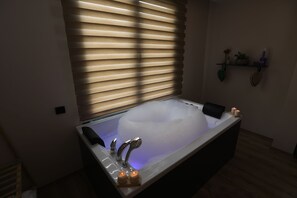 A modern bathroom with a freestanding bathtub, a vanity with a mirror, and a shelf with decorative items.