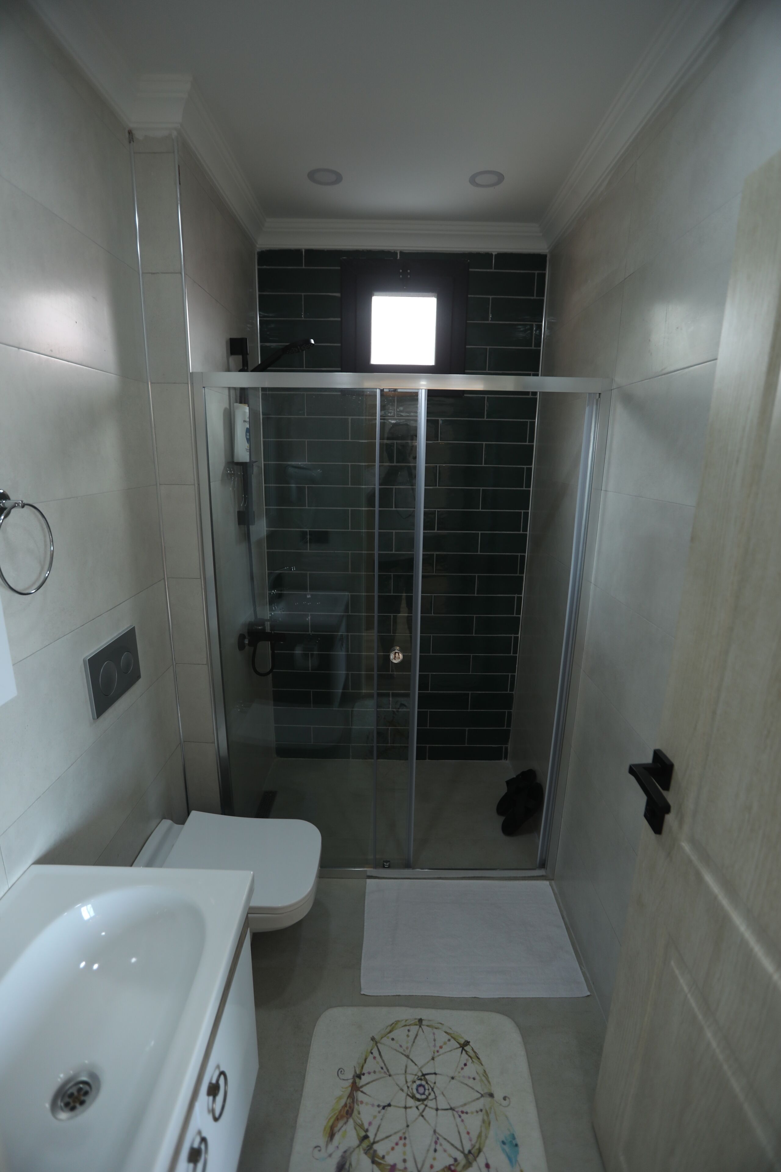 A small, modern bathroom with a glass-enclosed shower, a white toilet, and a bathtub.