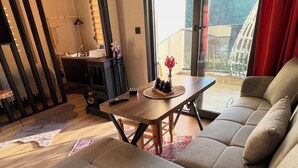 A modern living room with a sofa, a dining table, and a view of the outdoors.