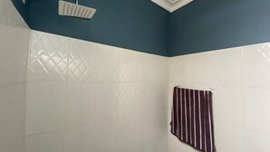 A bathroom with a shower, a towel rack, and patterned tiles. - Fully Furnished Studio Apartment (Tema)