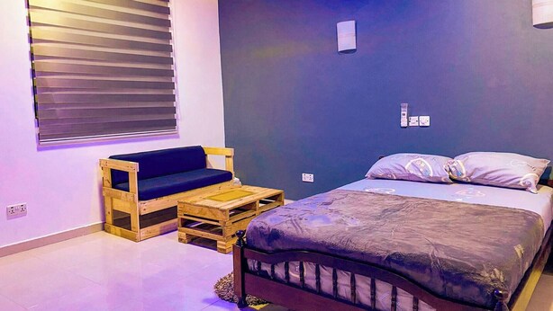 A bedroom with a bed, a wooden bench, and a small table. - Fully Furnished Studio Apartment (Tema)