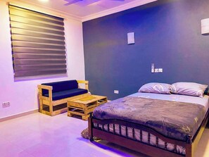 A bedroom with a bed, a wooden bench, and a small table. - Fully Furnished Studio Apartment (Tema)