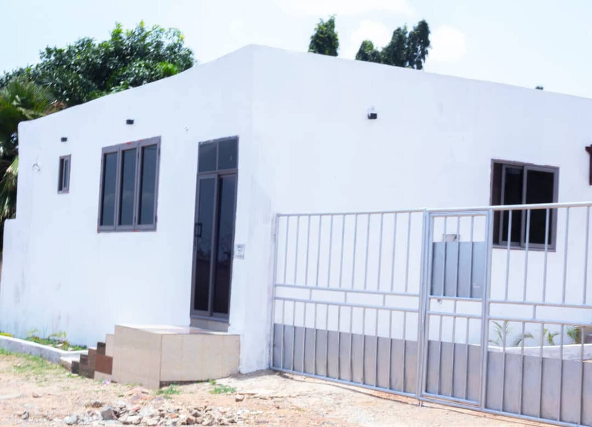A white building with a gated entrance, a door, and windows.