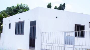 A white building with a gated entrance, a door, and windows.