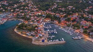 An aerial view of a coastal town with a marina, houses, and a bridge in the background.
