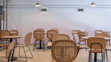 A modern cafe with wooden furniture and pendant lighting.