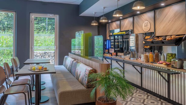 A modern cafe with a counter, seating area, and large windows.