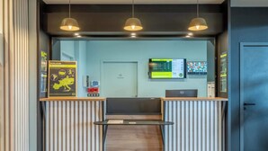 A reception area with a counter, a digital screen displaying information, and a door labeled "Local room".