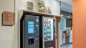 A vending machine and a self-service kiosk in a hotel lobby.