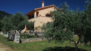 A two-story house with a stone wall and a garden.