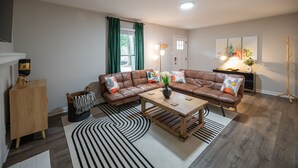 A modern living room with a sectional sofa, a coffee table, and a fireplace. - North Hills Oasis- 5mins from North Hills, Newly Renovated, Two En Suites!  (Raleigh)