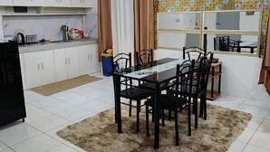Een moderne keuken met witte kastjes, een eethoek met een tafel en stoelen, en een grote spiegel boven de tafel.